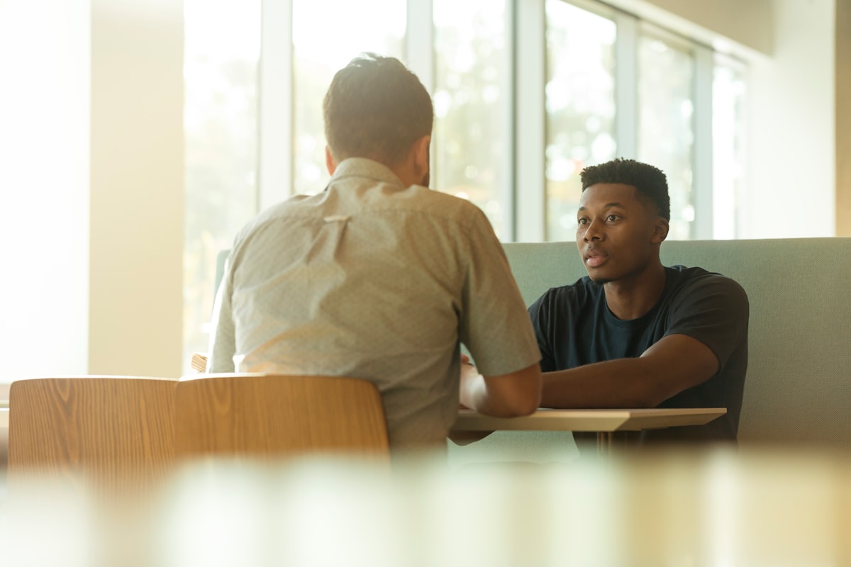 Two professionals in a focused one-to-one conversation by a bright window